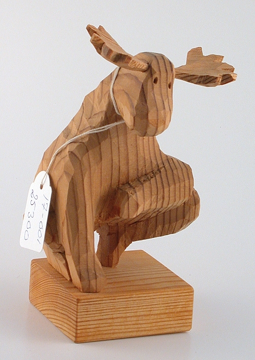 Träskulptur föreställande en älg, vilken är formad efter värmlandskartan, landskapets form.
Den snidade älgen är fästad vid en träkloss som fungerar som sockel.