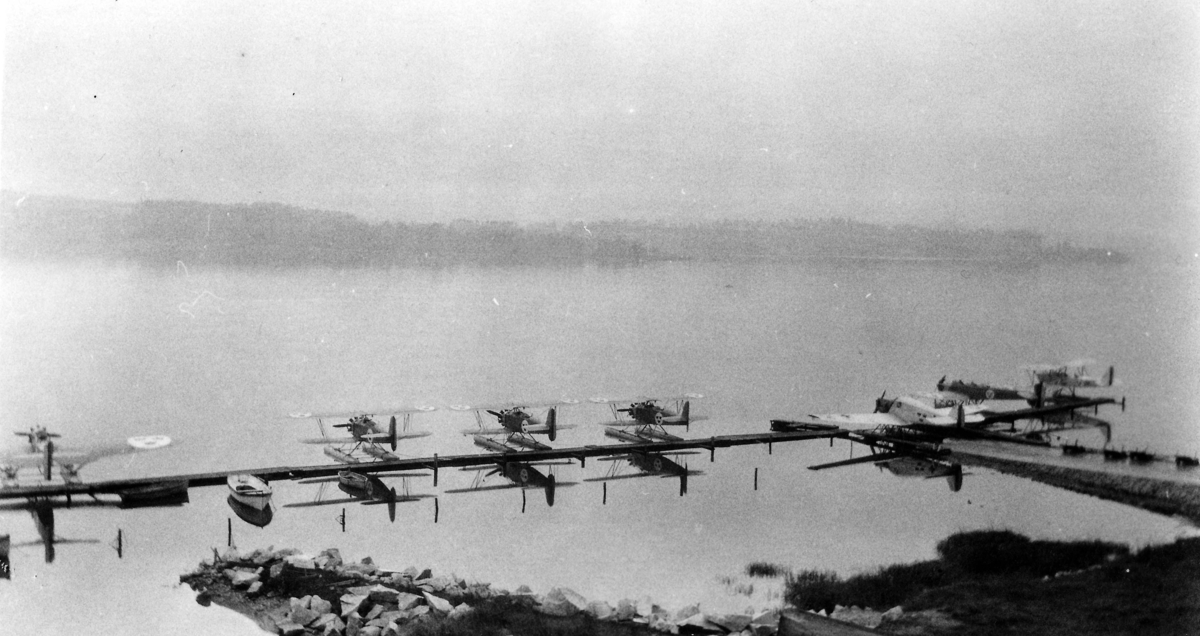 Sju militära sjöflygplan föränkrade vid brygga på F 2 Hägernäs, 1930-tal. Från vänster flygplan S 5, tre flygplan J 4, Trp 1, S 5 samt Sk 9. 1930-tal.