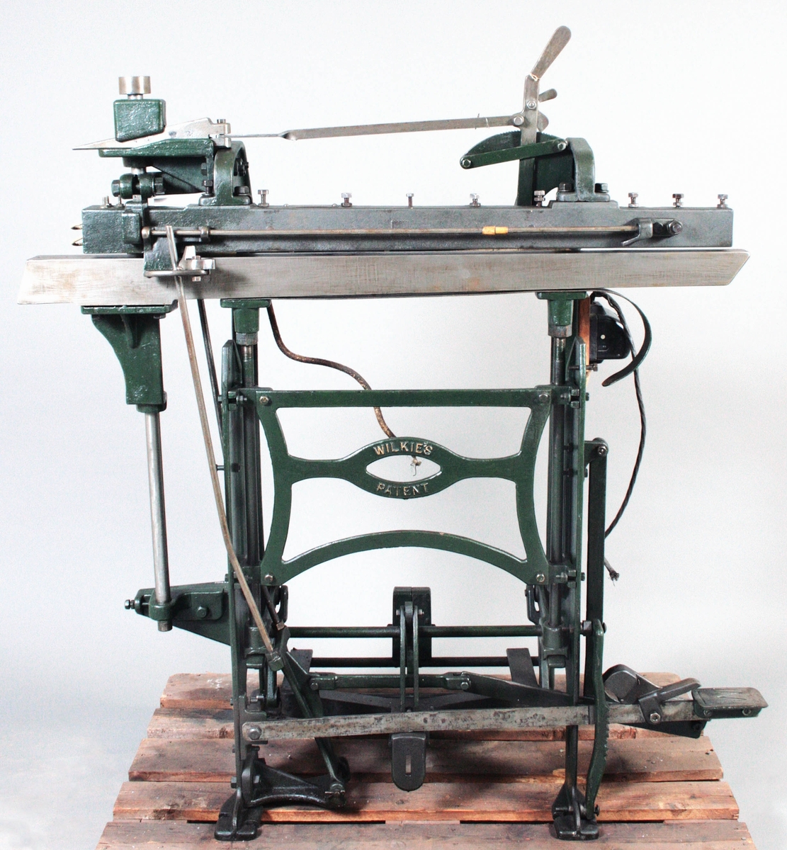 Pressmaskin för raka sömmar. Järnkonstruktion, delvis grönmålad, med pedal. Märkt: Isaac Braithwaite & Son, 54 Wilkies pate. Proveniens J.A. Peterson, Målsryd.

Funktion: För pressning av raka sömmar