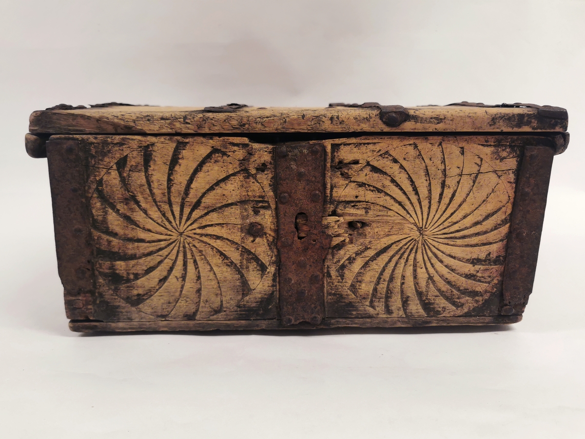 Ferdaskrin av tre med metallbeslag.  Ornament av spiral eller vifteform skåret på lokk og sider.