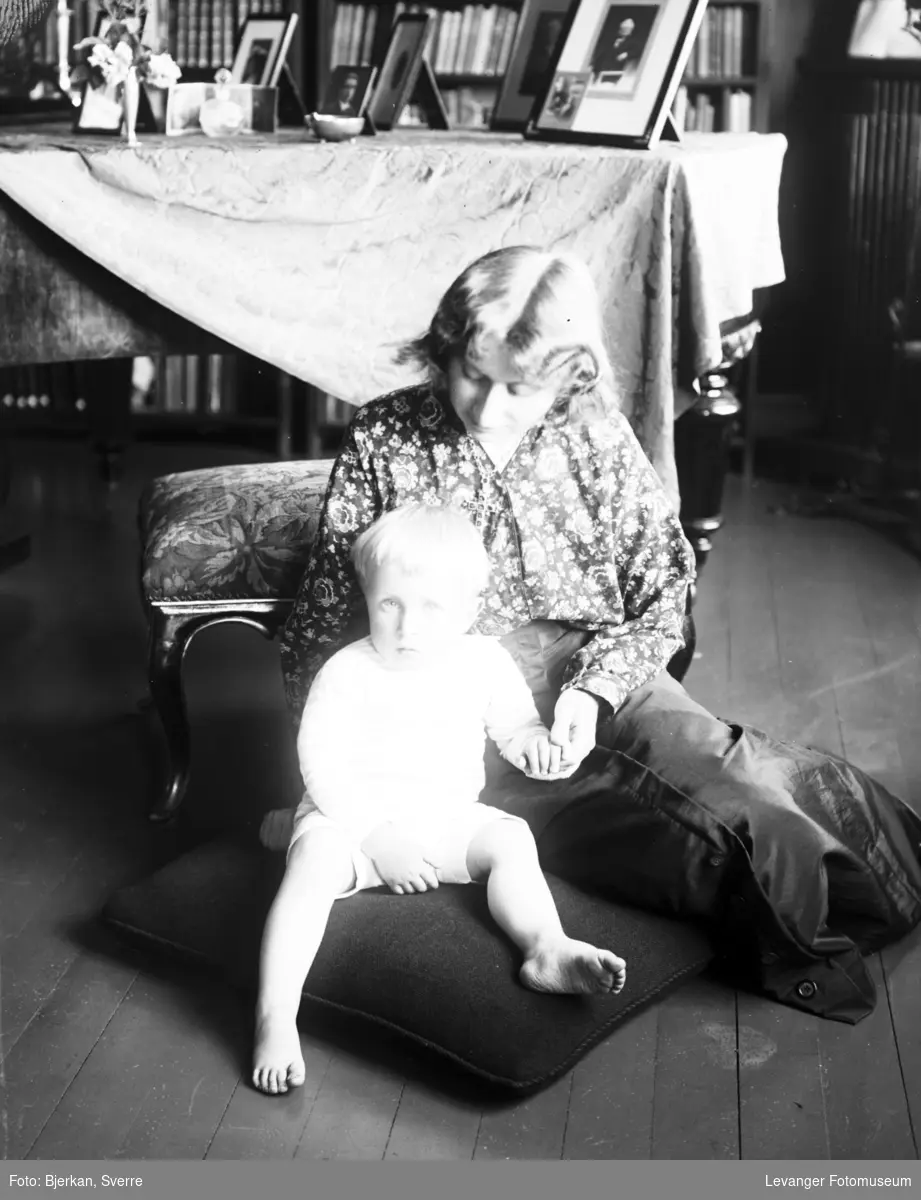 Portrett av kvinne med barn i stueinteriør