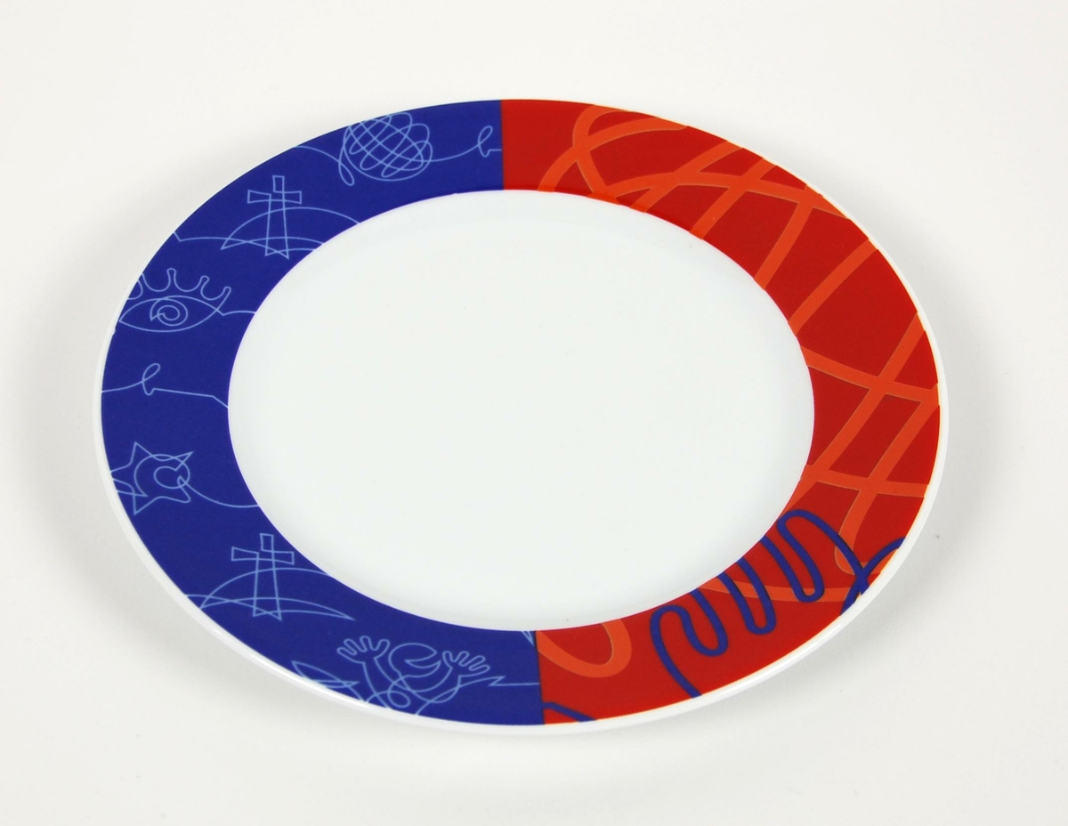 Liten tallerken/asjett av porselen med trykt dekor på kanten. Dekoren er en bord trykt i rødt og blått med mønster i oransje og lyseblått. Dekoren er utsnitt av millenniumsfeiringens piktogrammer.
