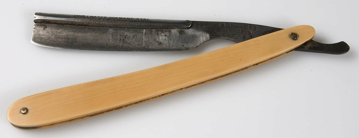 Hopfällbar rakkniv med skaft av gult ben och blad av stål med skena över ryggen med text: Trollhätte Diamant-stål, stämplad J A H Fullberg, Eskilstuna, Sweden.