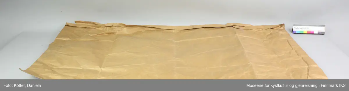 Papirposen er laget av brun papir og har en åpning på langside. Den har påført en etikett og har kostet 1,40 kroner.
