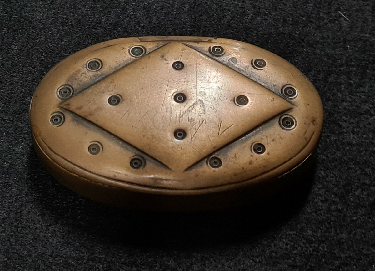 Snusdosa av mässing, oval form med ringornament på locket. 03 107-03 109 köpta av Gustav Svensson Takan, Gestad socken, Dalsland för 1,50:-.