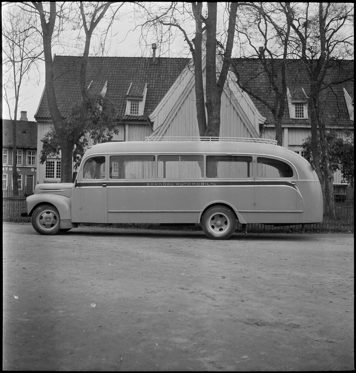 En buss av merket "Ford" fra "Sokndal Automobil A/S" på gamle Egersund rutebilstasjon. Egersund kirke er i bakgrunnen. Bussen gikk i ruta Hauge-Åna-Sira.