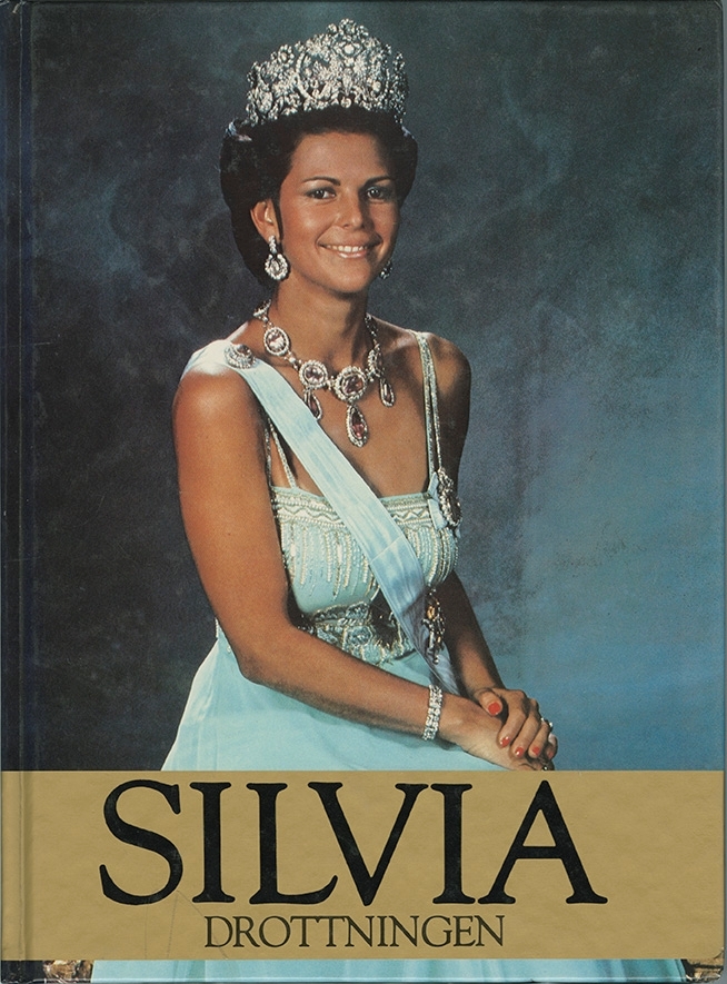 Silvia Drottningen. Bok av Christine Samuelson. 

På bokens framsida är en bild på drottning Silvia iklädd krona, smycken och ljusblå klänning. 
