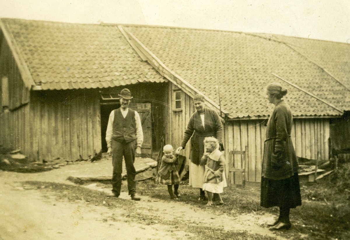 Tre vuxna och två små barn står utanför ladugården vid Livered "Majas" (idag: Streteredsvägen 36) cirka 1900-1910. Från vänster ses Karl Andersson, en okänd kvinna med två små barn samt Karin Andersson (Karls dotter).