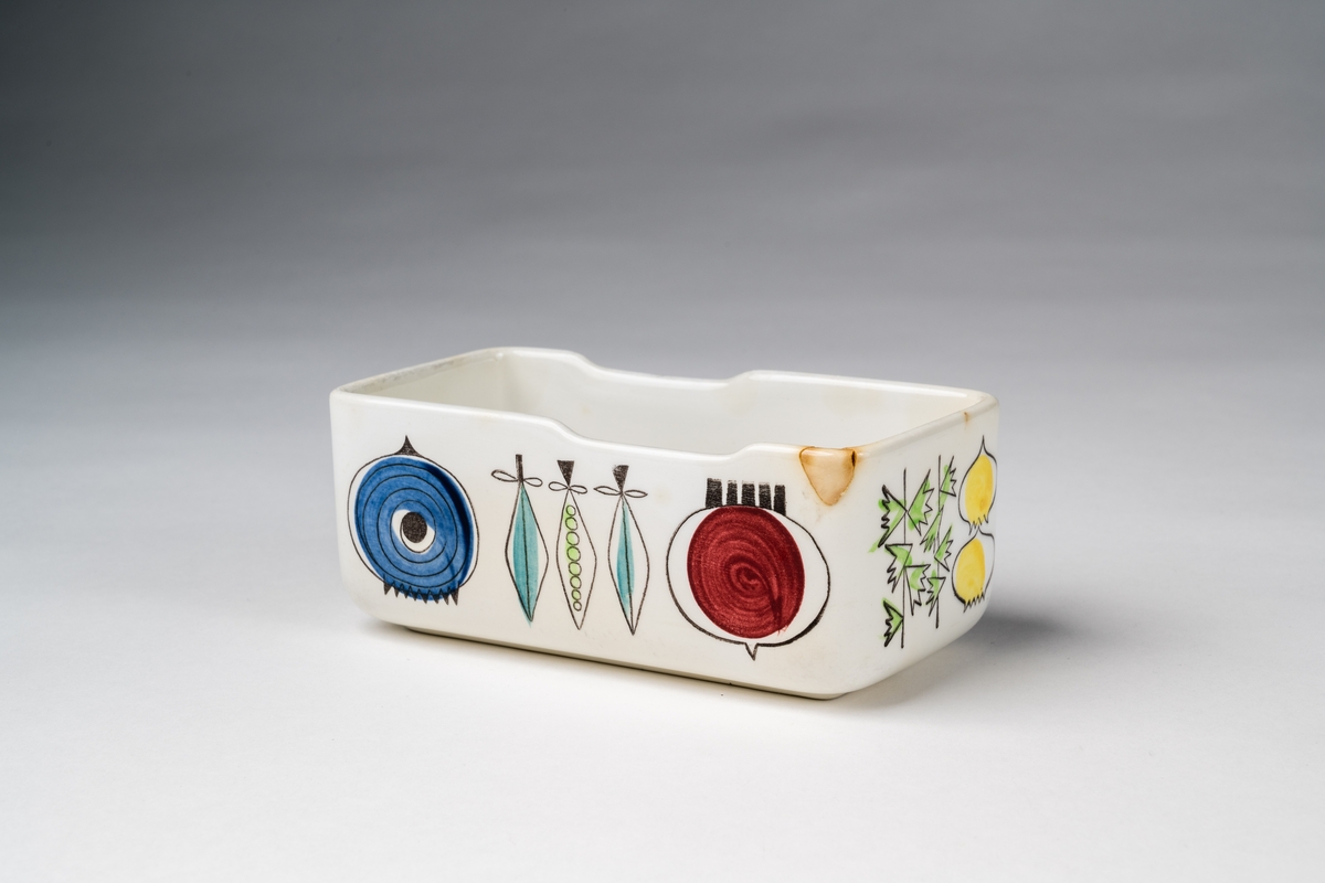 Keramikask, smörask, med stämplad och målad dekor, som föreställer olika grönsaker. Märkt under botten på burken: "PICKNIK Rörstrand SWEDEN HANDPAINTED 56".