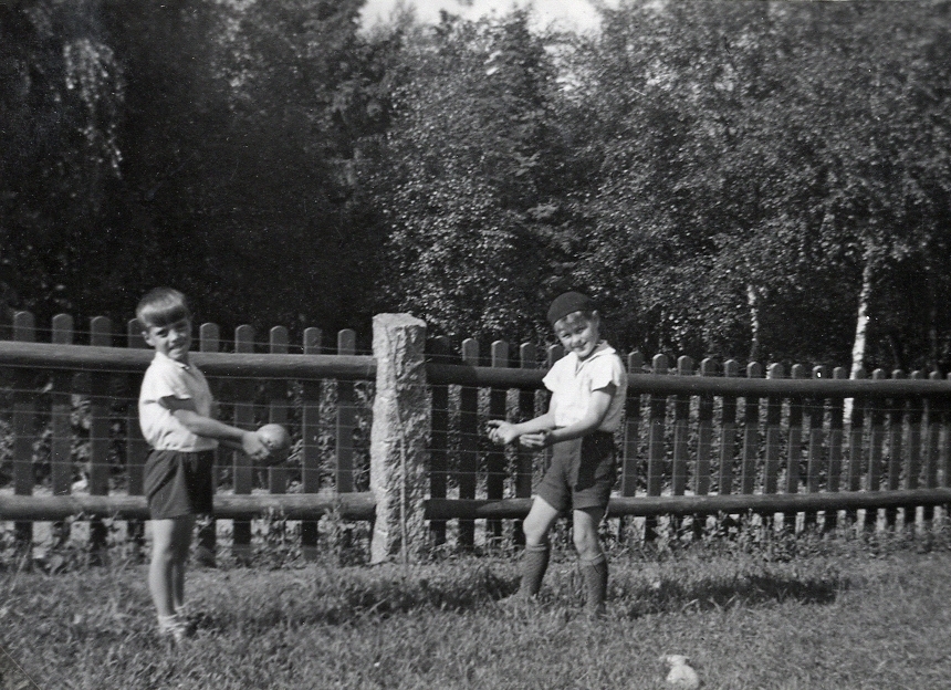 Två pojkar leker med en boll i en trädgård.