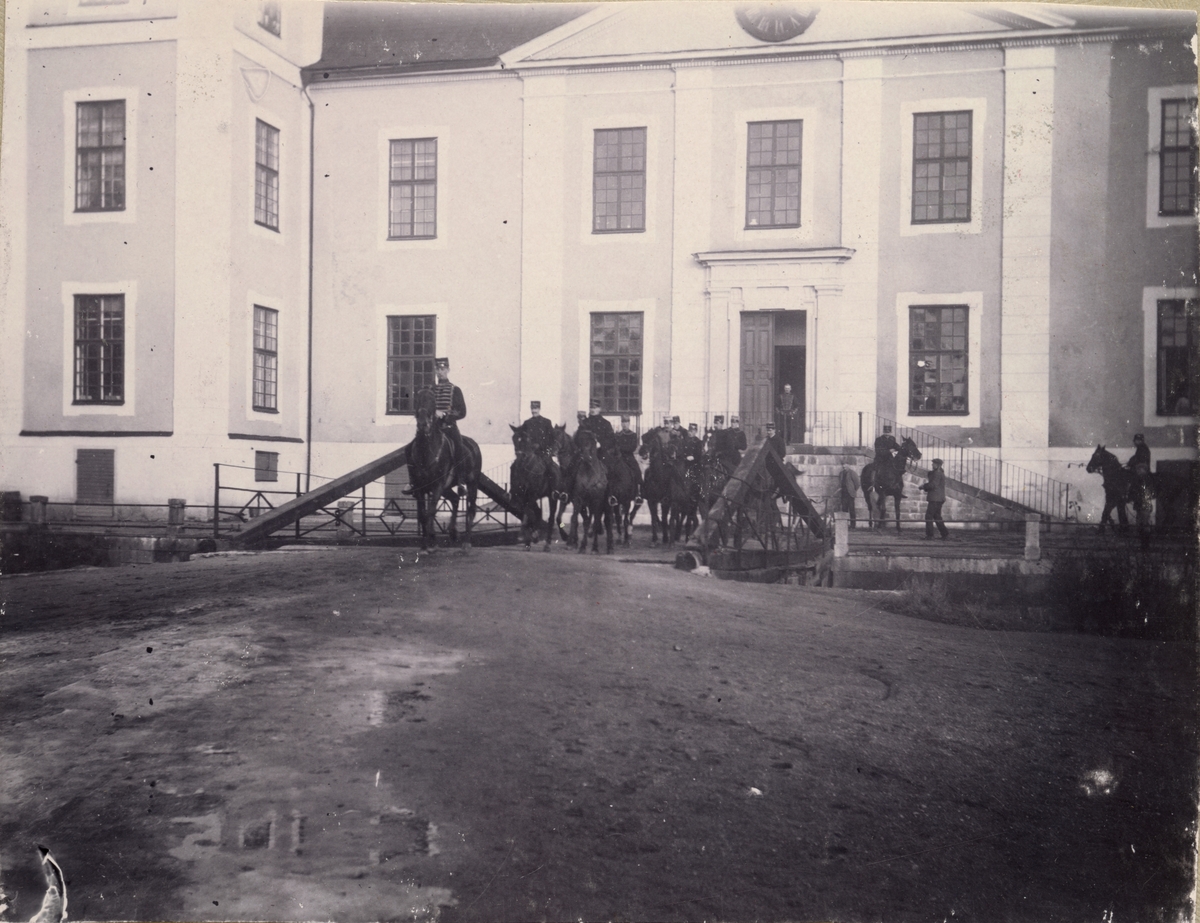 Soldater till häst framför en byggnad.