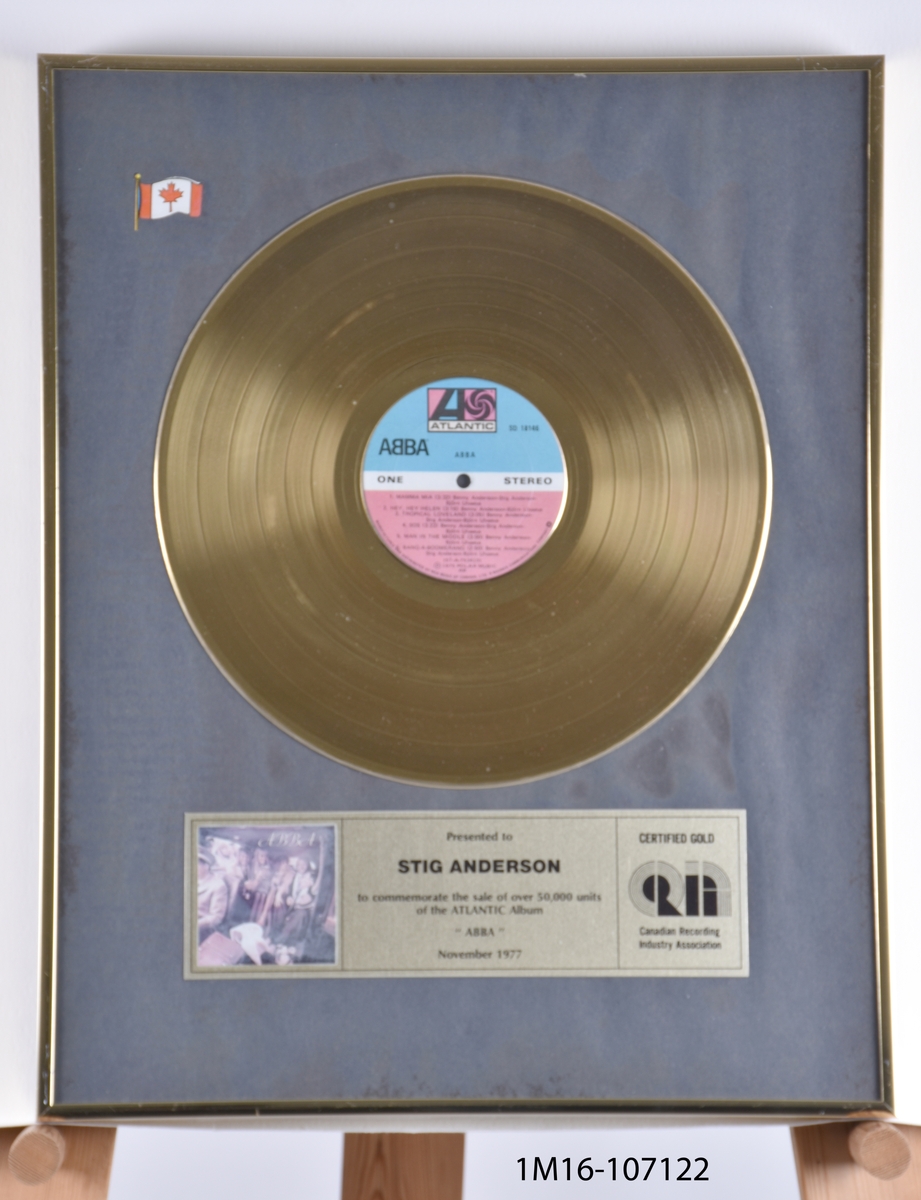 Guldskiva utfärdat till Stig Andersson för att albumet ABBA sålts i fler än 50 000 exemplar i Kanada. Guldskiva mot svart bakgrund. Plakett under skiva. Kanadas flagga i övre vänstra hörn. Utfärdat av Canadian Recording Industry Association.