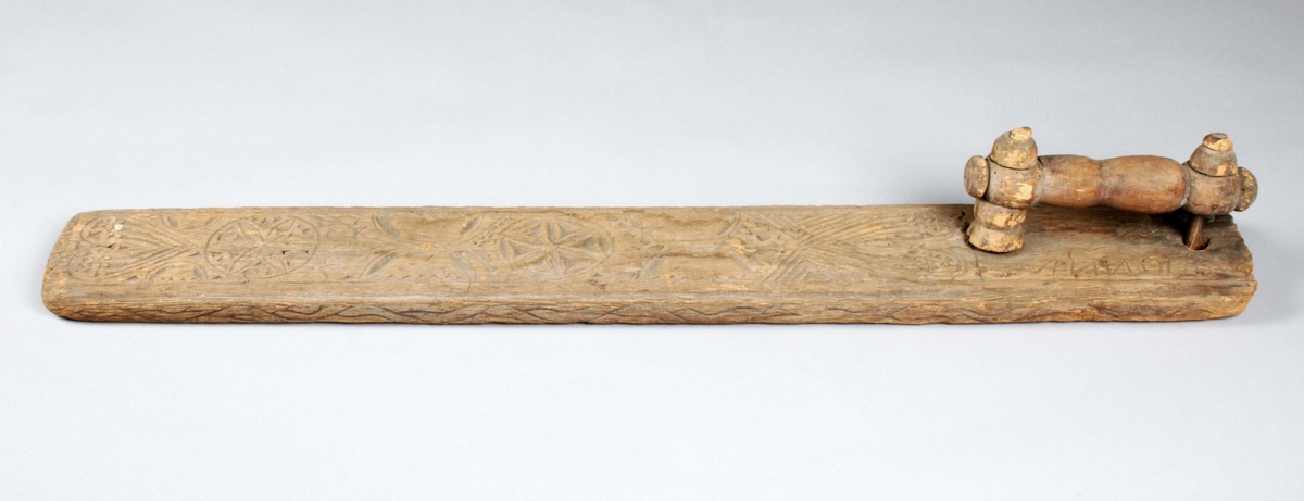 Mangelbräde i brunbetsat trä. Bruks- och färgslitage. Handtaget svarvat (en del saknas, lös). Brädet med karvsnittsdekor, i form av våglinjer på kanternas sidor. Översidans kanter profilerade, samt inom dessa, bladrosetter, hjärta, bladformationer samt streckformationer. Skuret på ena ändan: "IED ANNO 1745"

Mangelbräde eller kavelbräde är ett redskap av trä som använts för mangling av textilier. Mangelbrädet användes tillsammans med en kavel, en slät rulle av trä. Den textil som skulle manglas, rullades upp på kaveln, på ett bord eller annat slätt underlag. Under hårt tryck, rullades kaveln med hjälp av mangelbrädet, fram och tillbaka över bordet. (Wikipedia)