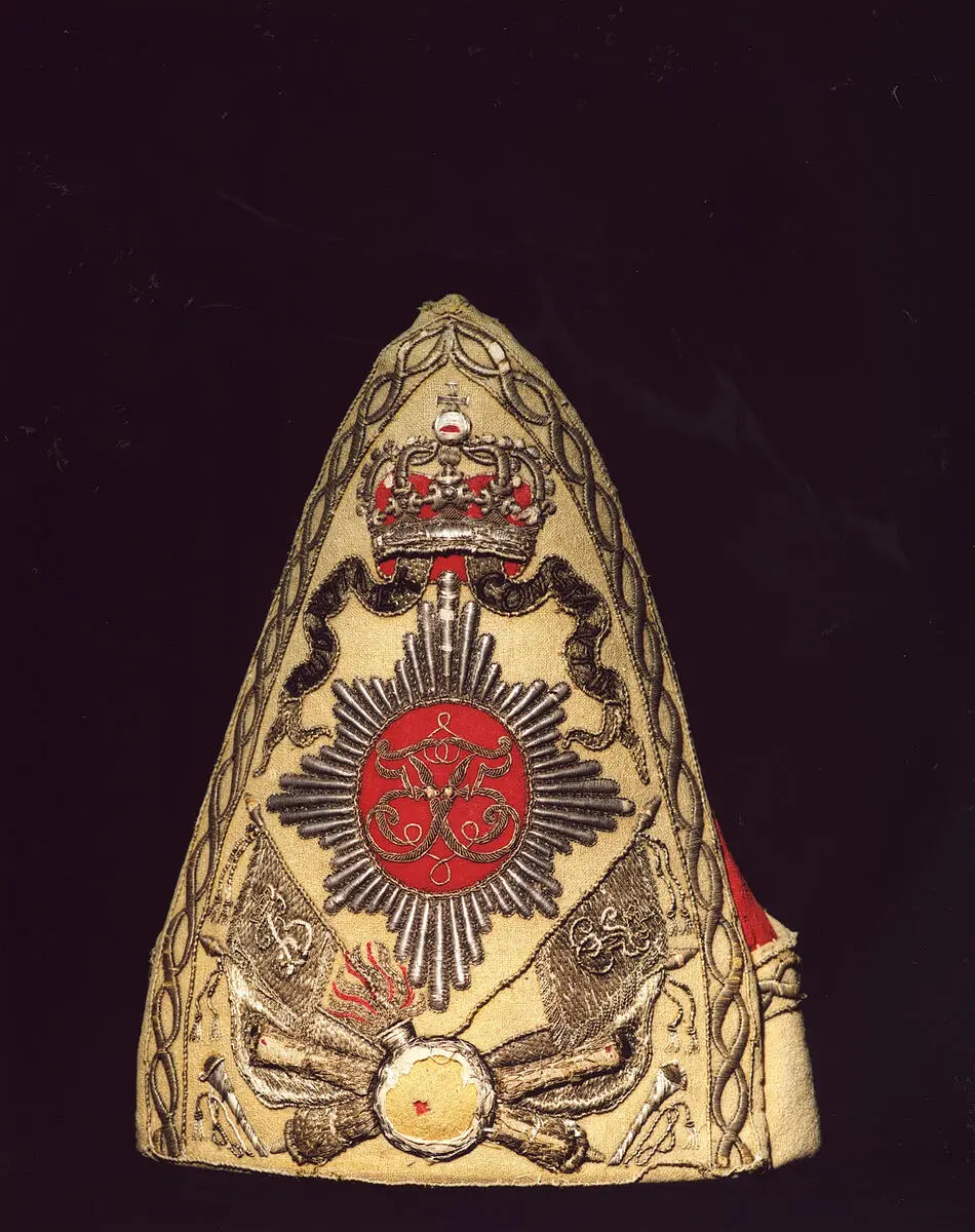 Hodeplagg med motiv av krone, monogram, bannere, kanoner o.l.