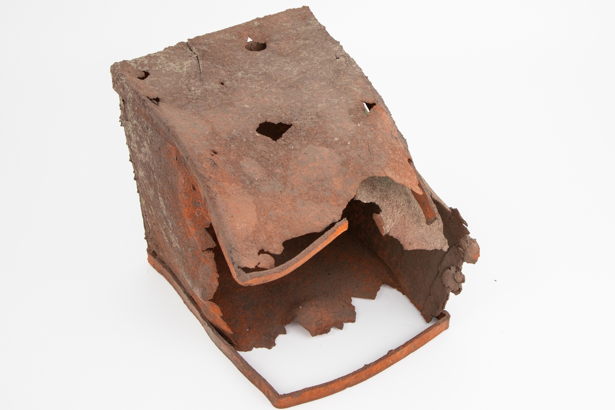 Håndlaget keramikkskulptur som imiterer rustent metall. Formen ligner en boks som ligger med åpningen på siden, delvis sammentrykt, hullete og erodert. Frynsete, skarpe kanter.