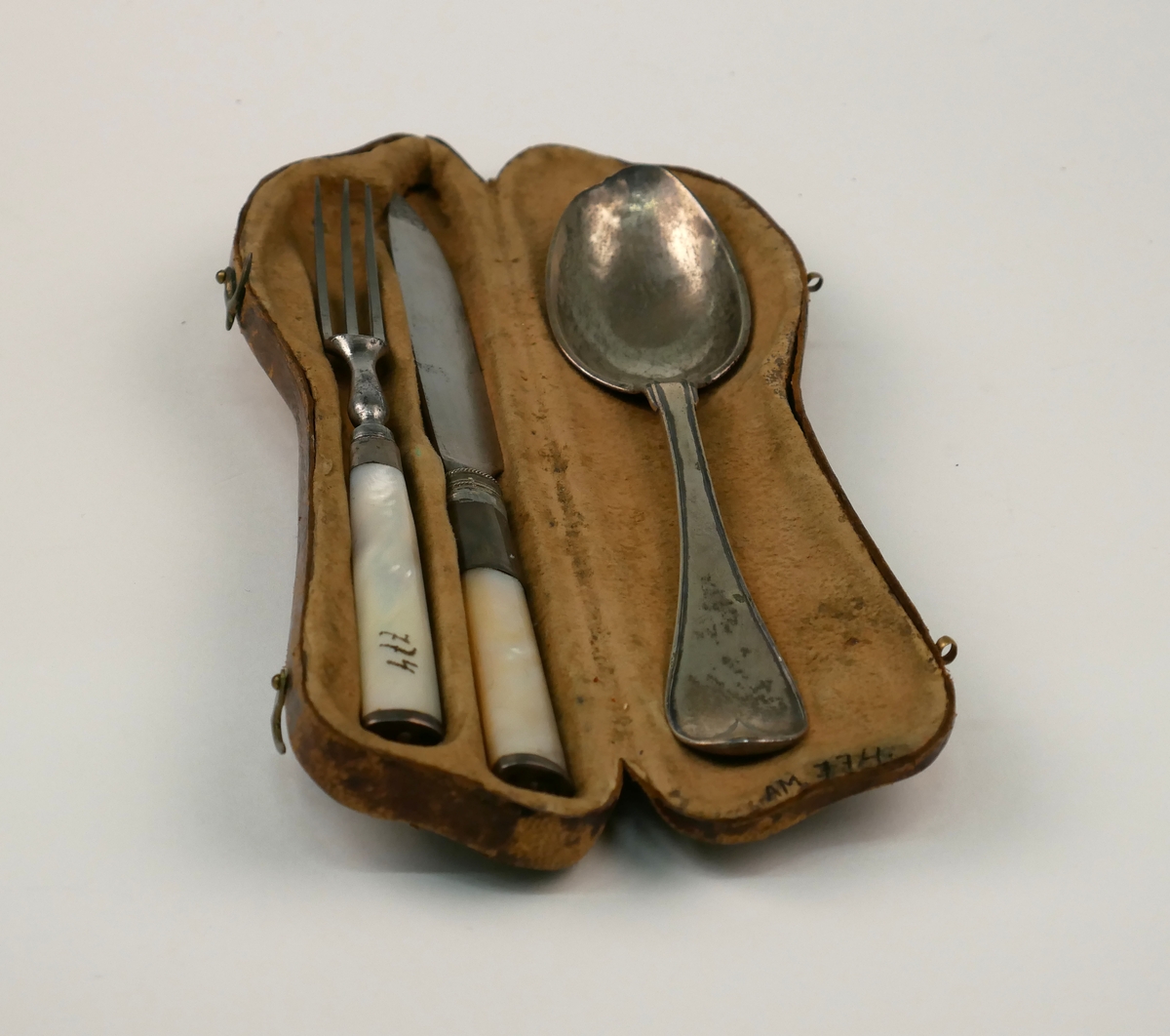 Ett etui med en uppsättning resebestick, kniv, gaffel och sked av silver. Kniv och gaffel med skaft av pärlemor.
Skeden dekorerad med monogram "FML" och stämplad med årsbokstav: F2=1788 samt "Eneroth" = guld- och silversmed Petter Eneroth (1741-1809) mästare från 1771.