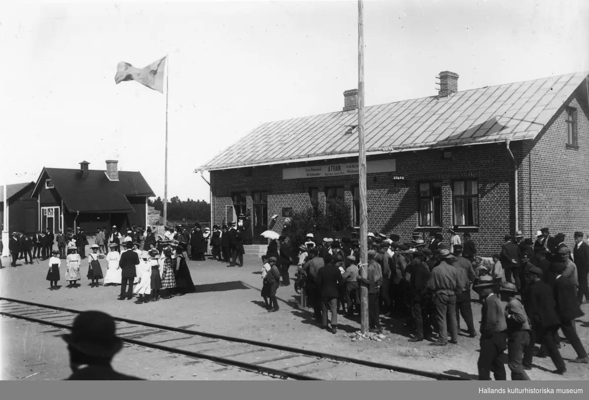 Invigning av Ätrans nya stationshus och Varberg-Ätrans Järnväg 1911-07-22. En stor folkskara har samlats för festligheterna. Till vänster syns den äldre stationsbyggnaden som hört till Fegen-Ätrans Järnväg invigd 1887. Villkoret för att Varberg-Ätrans Järnväg skulle få ansluta till den befintliga stationen var att man förutom nytt stationshus även uppförde ett nytt godsmagasin och bekostade banområdets utvidgning. Fram tills dess hade järnvägen från Fegen slutat här med Ätran som s k säckstation.