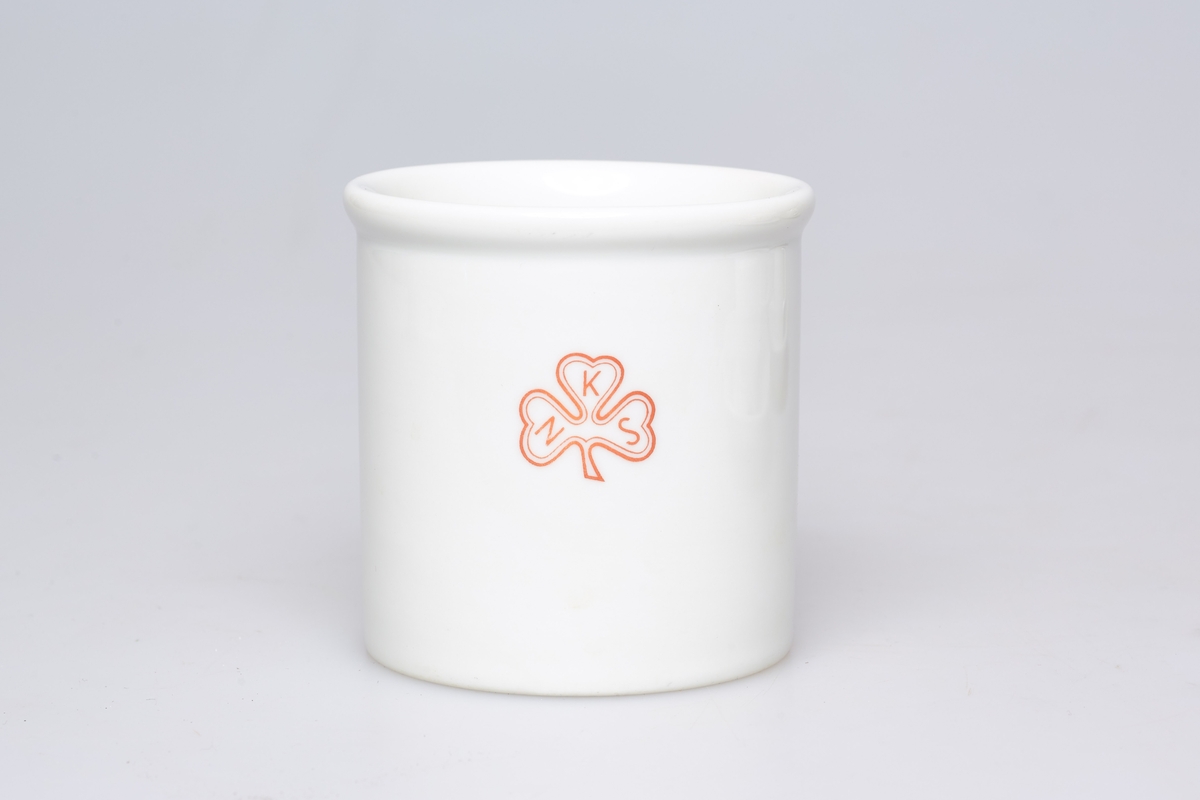 Stor kopp i porselen, med hank og logoen til Norske kvinners sanitetsforening. 