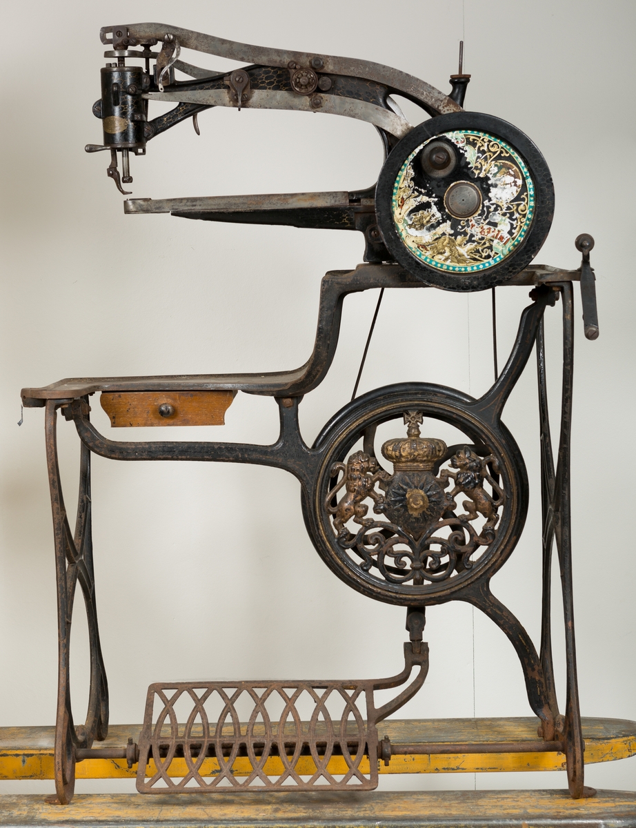 Manuell, pedaldrevet skomakermaskin, dekorert med en krone og to løver