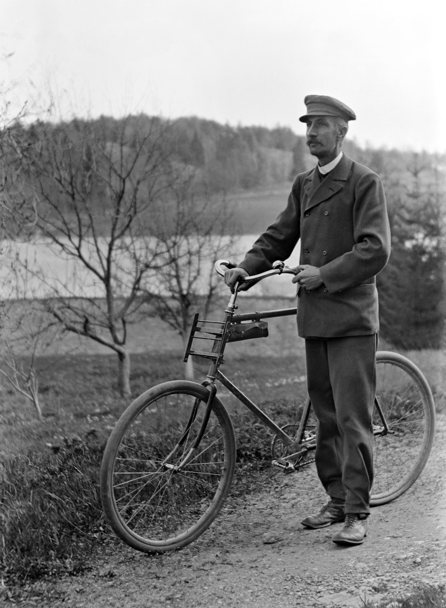 Fotograf Emil Durling poserar med cykel i äppelträdgården vid sitt hem Strömmen i Sankt Anna.