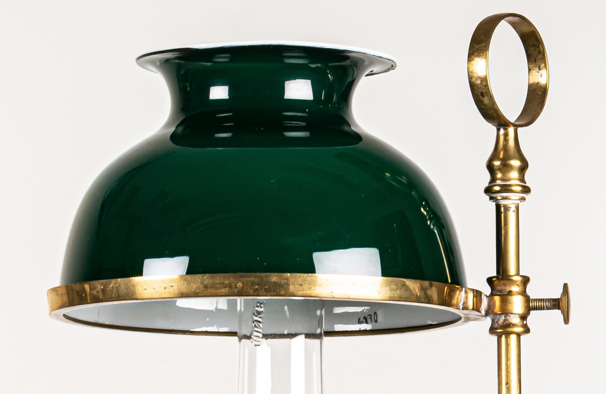 Bordslampa, av mässing, med grön porslingskupa. Hinks & sons patent.
På brännglaset John Surman, Stockholm.