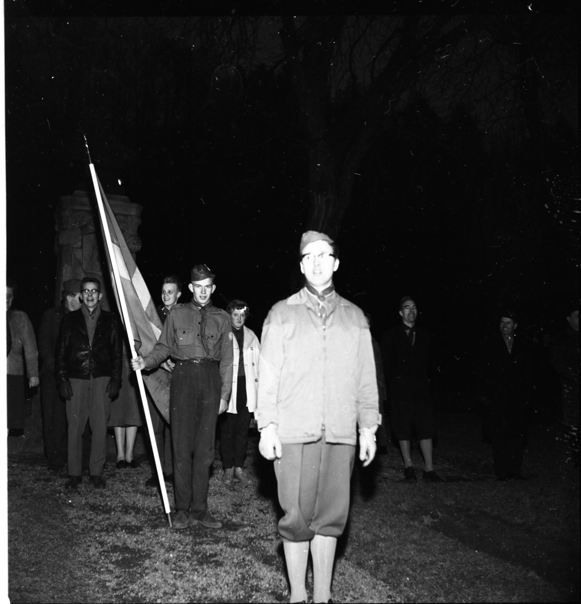 En scoutkår. I bakgrunden syns en scout hålla i en flagga.