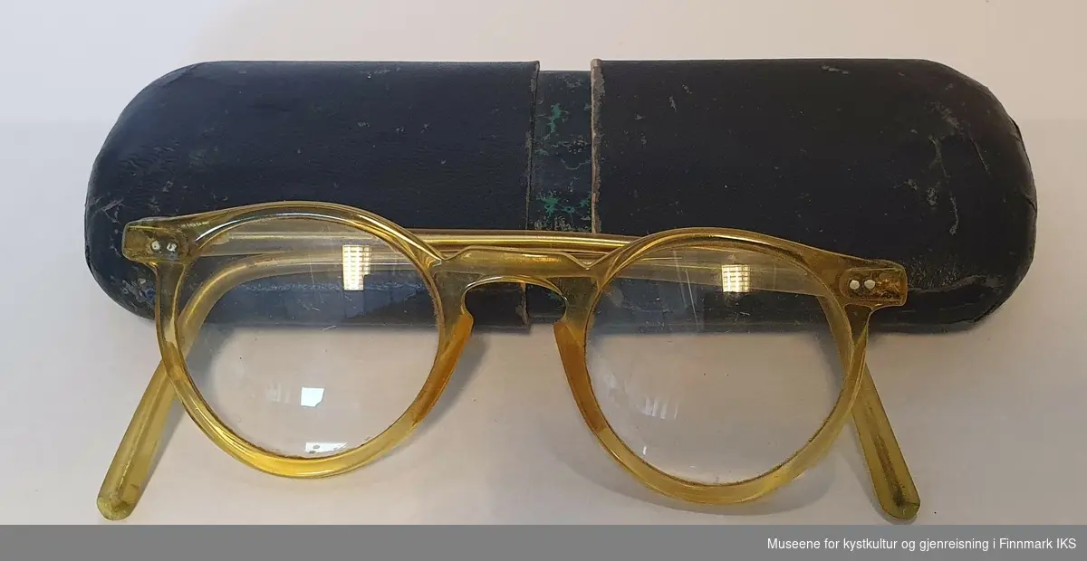 Svart  ovalt brilleetui med gule briller.