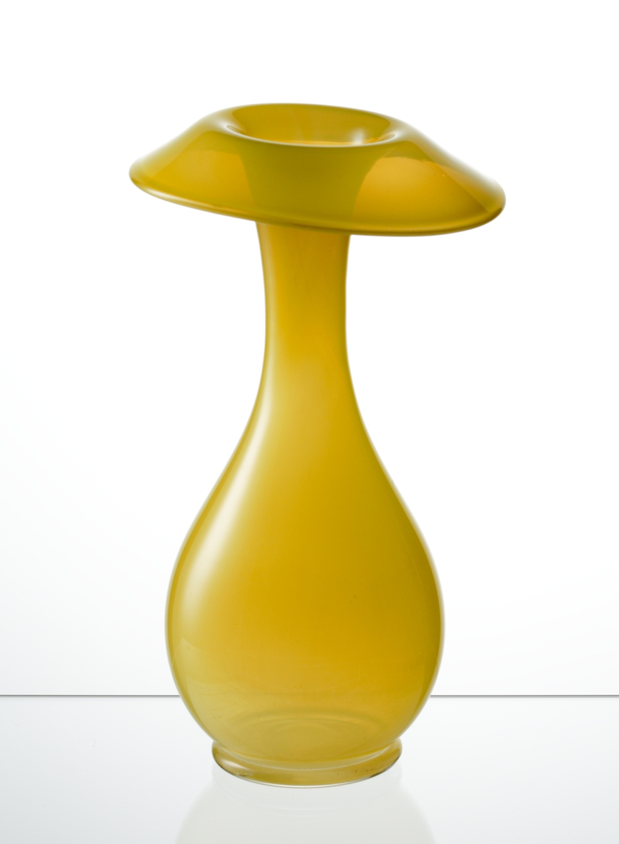 Design: Ingeborg Lundin.
Vas, opakt gult glas. Ovoid form med snedställd utvikt mynning.
Orkidévaserna visades första gången på NK 1948.