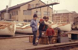 Felt 1967. Hjemtransport. Havn med båter. Kasser Feltutstyr 