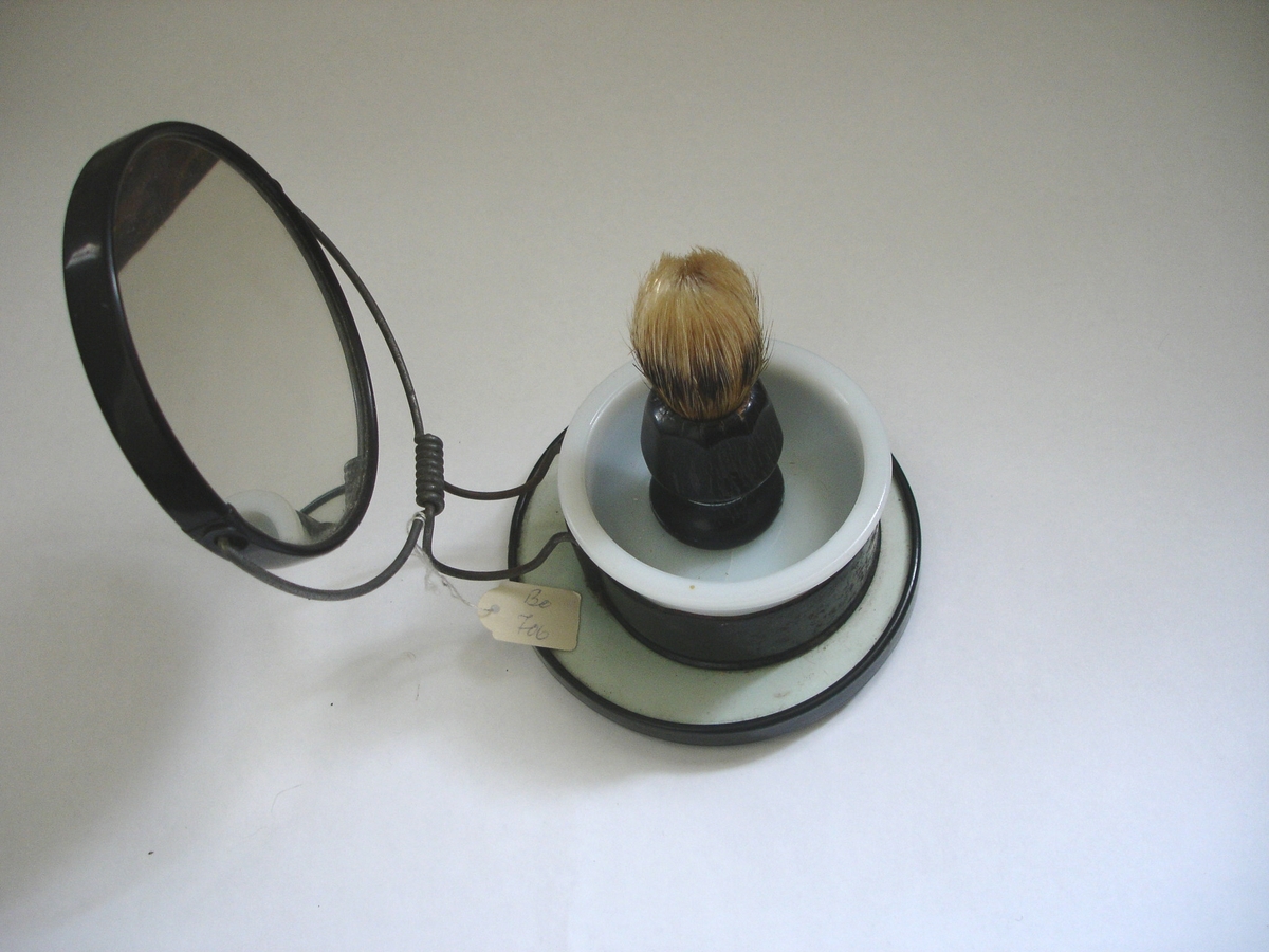Et barbersett som består av en kost og ei lita skål med speil.