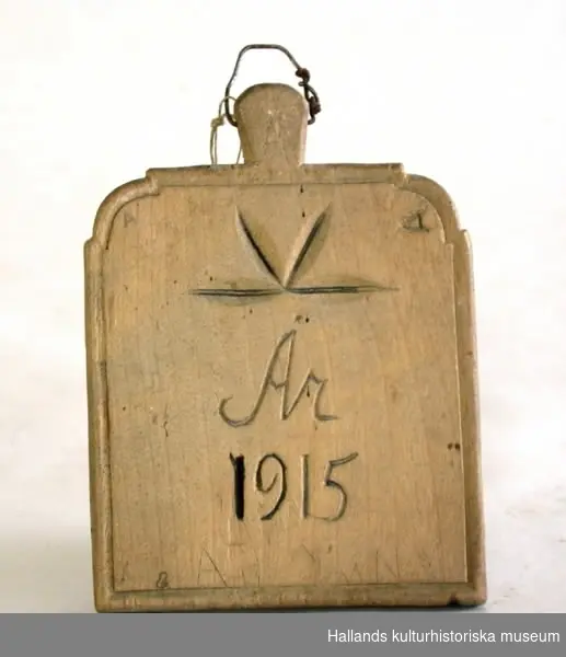Träbricka med skuren text: "Källsjö Församlings Ringtavla År 1915".