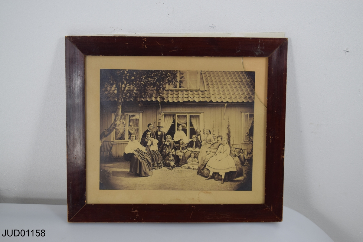 Inramat fotografi föreställande familjen Levertin på Hesslingeberg, Djurgården samt dokument med förteckning över avbildade personer i plastficka. Okänt årtal