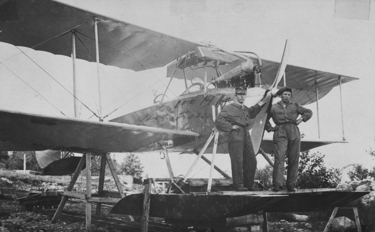 Flygplan SW 20 nummer 754 står uppställd på bock. Två mekaniker står vid flygplanets nos. Under provflygning med flottörer vid Bergs slussar, 1917.