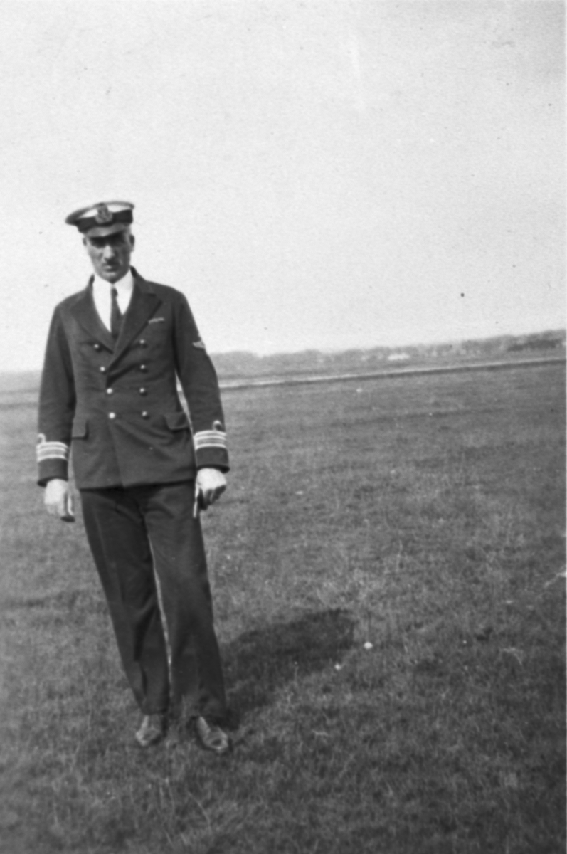 Porträttfotografi av chefen för F 5 Krigsflygskolan, kommendörkapten Arvid Flory ståendes på ett flygfält.