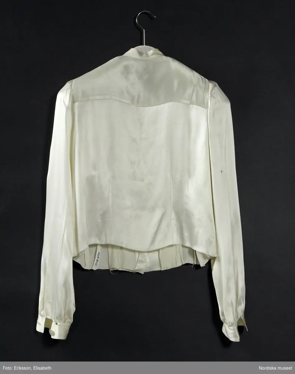 Ordered by Nanna Svartz (1890–1986), physician, Doctor of Medicine and Sweden’s first female professor at a state university in 1937.
Delivered June 1937. Silk tailcoat and long, slim skirt. Nanna Svartz wore the jacket with a cream silk pussy-bow blouse with mother of pearl buttons. Her monocle (eyeglass) was kept in the breast pocket. At her ceremonial installation she also wore the traditional doctor’s hat. The emblem of the medical profession is embroidered in silk on the velvet collar.