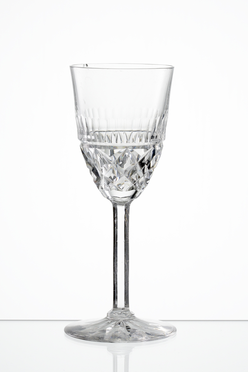 Design: Okänd. 
Sherryglas med lätt klockformad kupa, skärslipad nedre del med olivslipad bård. Fasettslipat högt ben. Fot med skärslipad
stjärna i botten.
