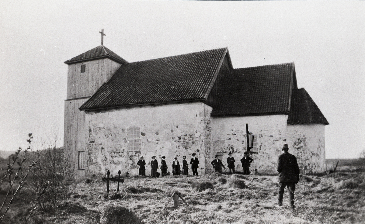 Romnes kyrkje i Nome kommune med personar framfor