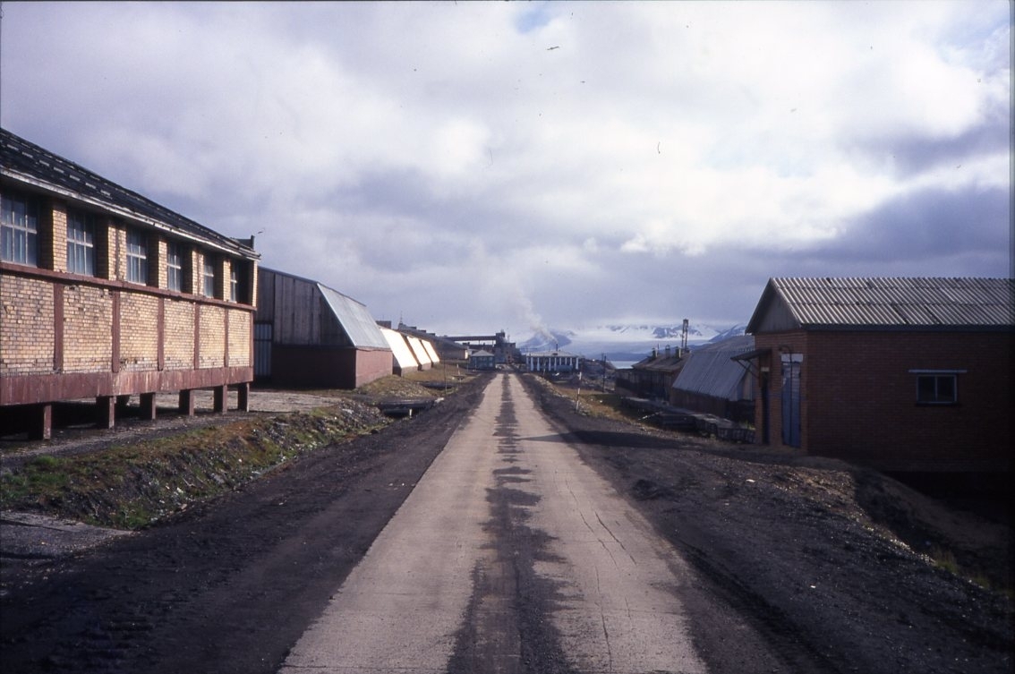 En rak grusväg kantad av byggnader i det ryska gruvsamhället Barentsburg på Svalbard.
