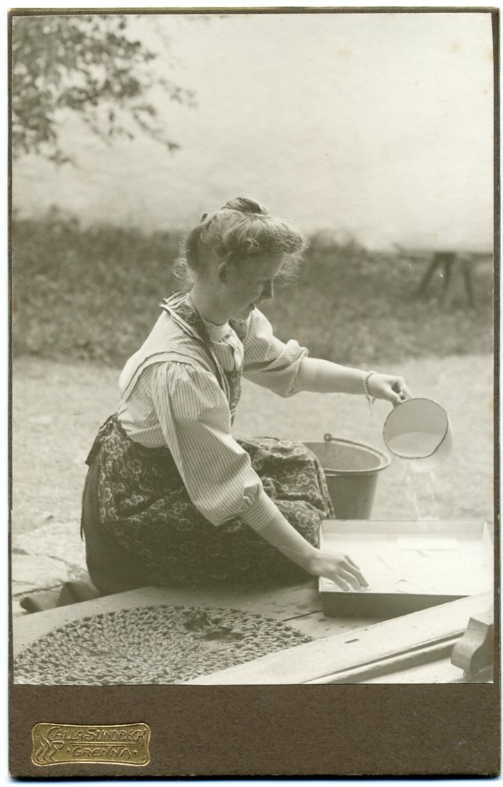 En ung kvinna sitter på en farstutrappa och sköljer fotografier i samband med framkallning.