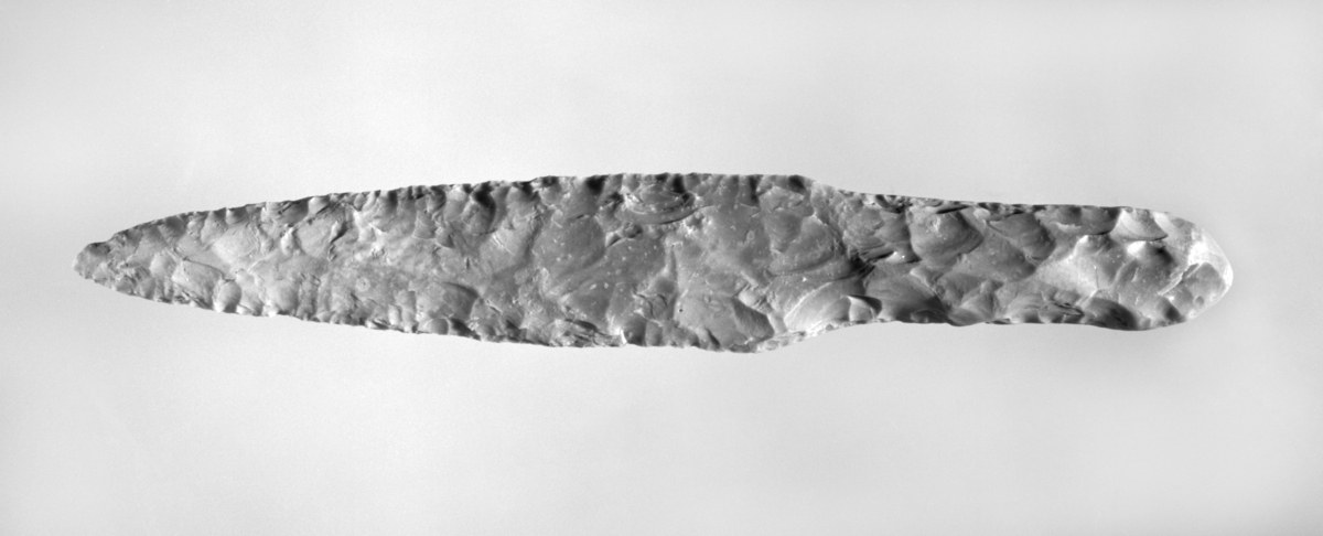 Flintdolk av type II B i E. Lomborg "Die Flintdolche Danemarks". L. 24,1 cm, st. br. 3,8 cm, br. over skaftet 2,5 cm. Funnet i oppgravde jordmasser som kan ha kommet fra gården Blindheim, men dette er langt fra sikkert. Ålesund, Møre og Romsdal