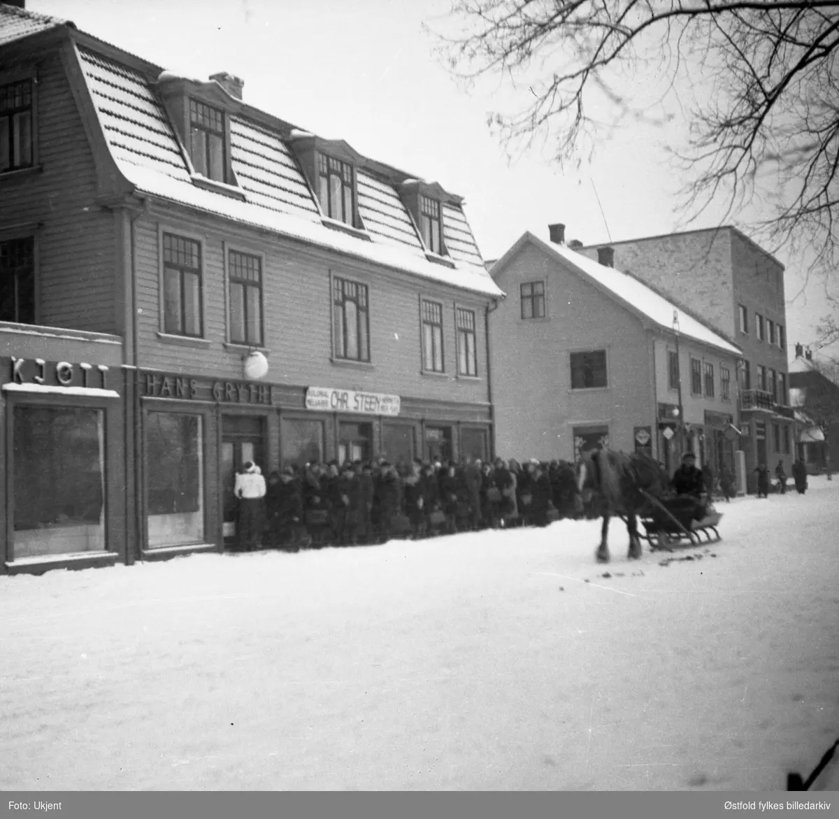 Folk i kø for kjøtt og fisk under 2. verdenskrig i Askim 1940-1945 Kolonial til Chr. Steen og kjøttforretningen til Hans Grythe i Jernbanegata.
