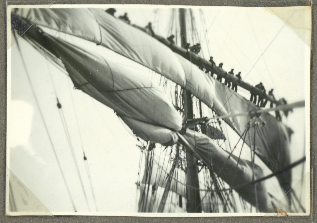 Bilden visar skeppsgossar som arbetar i riggen på af Chapman med sättningen eller bärgning av segel.