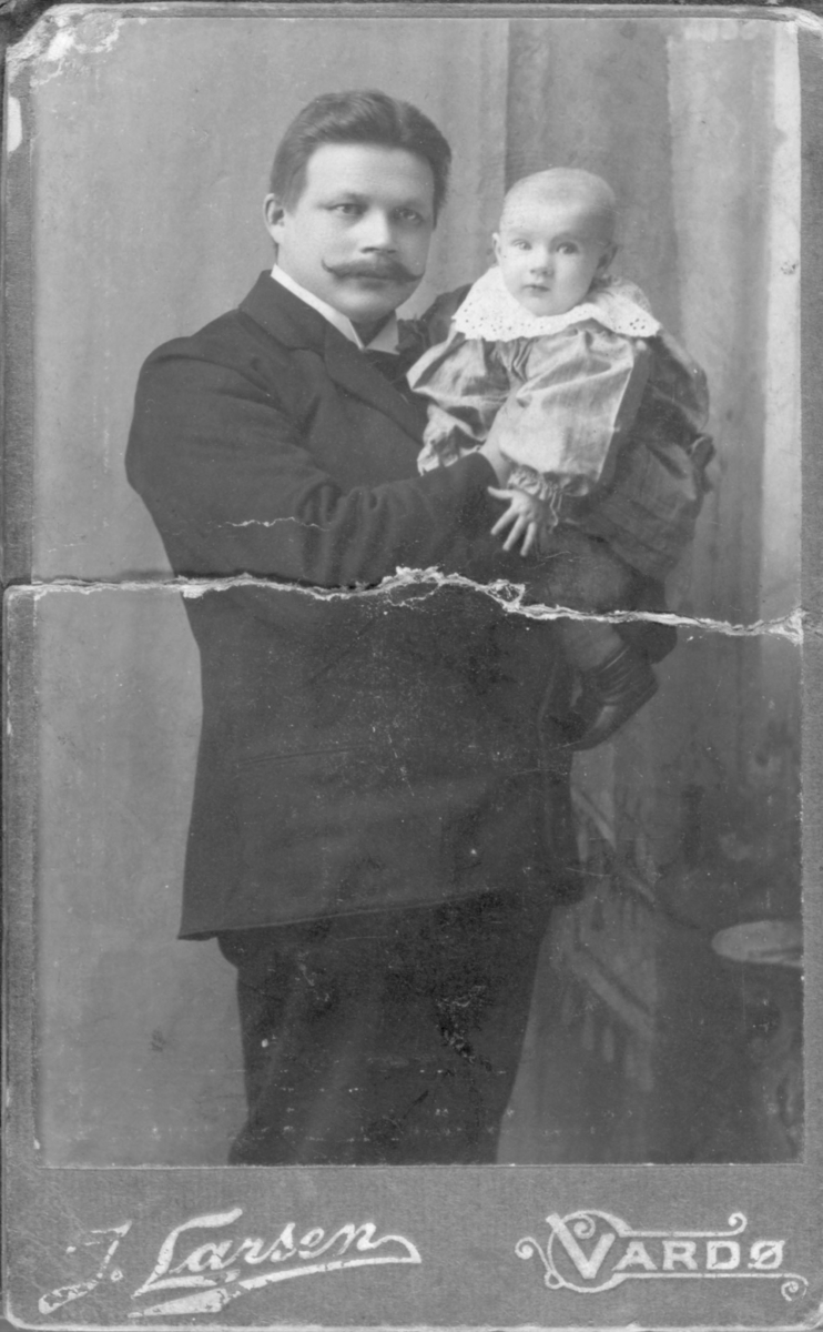 Et visittkort med portrett av fotograf Jasper Ulrik Soini med et lite barn, hans sønn Leofred. Gutten døde i alderen 3 år (1904-1907). Barnets mor giftet seg med en annen før barnet ble født og flyttet til Vardø. Soini døde av tuberkulose i 1905 og var ugift.