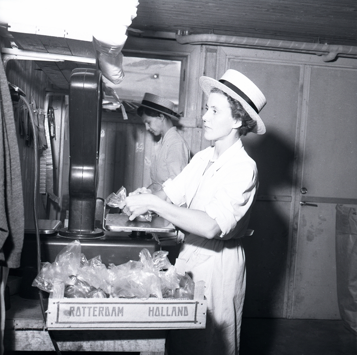 Två kvinnor står och arbetar vid en våg i en konsumbutik.