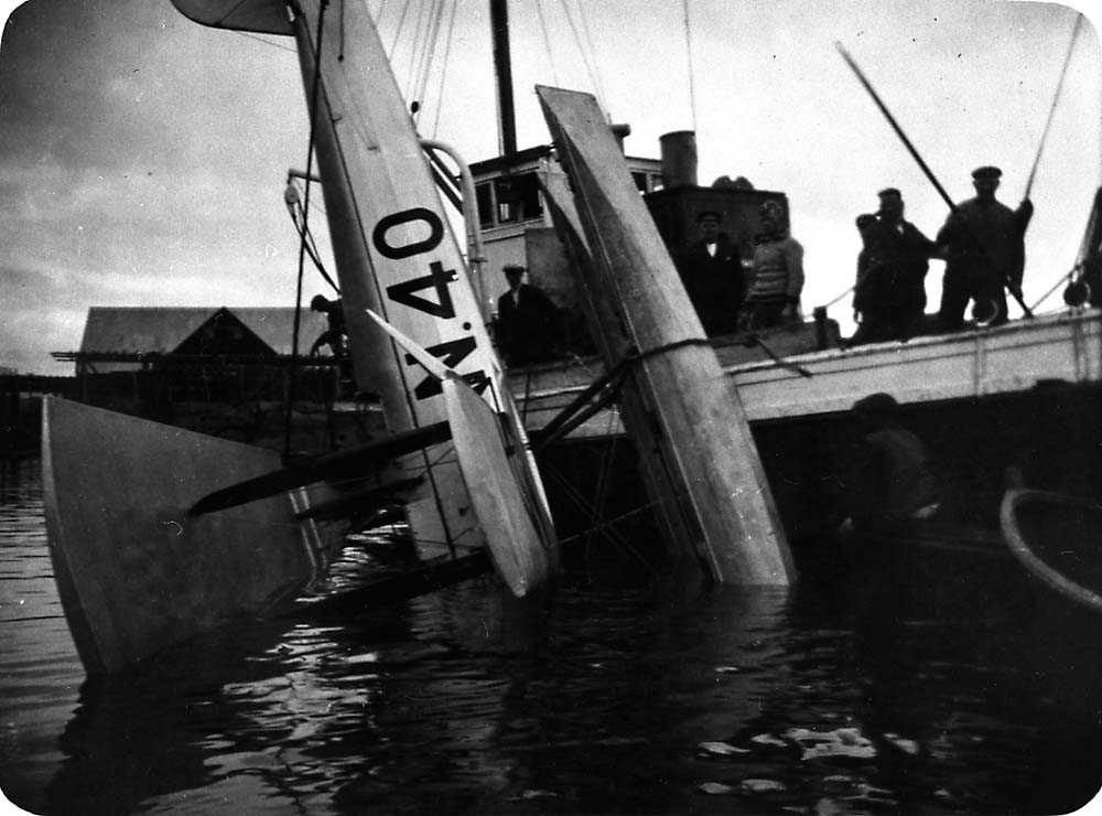 Ett sjøfly som blir heist opp av vannet etter et havari, Saaski "Måsen". To båter med flere personer i.