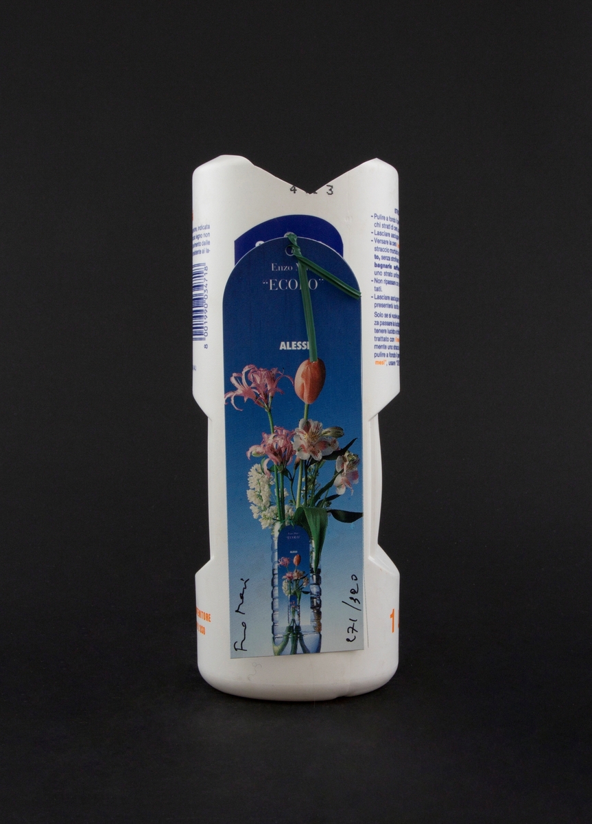 Vase laget av plastflaske for gulvpoleringsmiddel. Kort med bilde av blomster i vase er festet til vasen med et grønt feste.