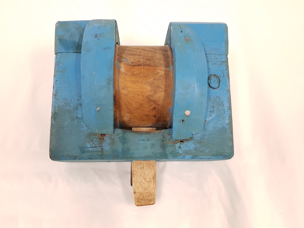 Et stykke tre blåmalt med en trommel midt på inne i klossen
