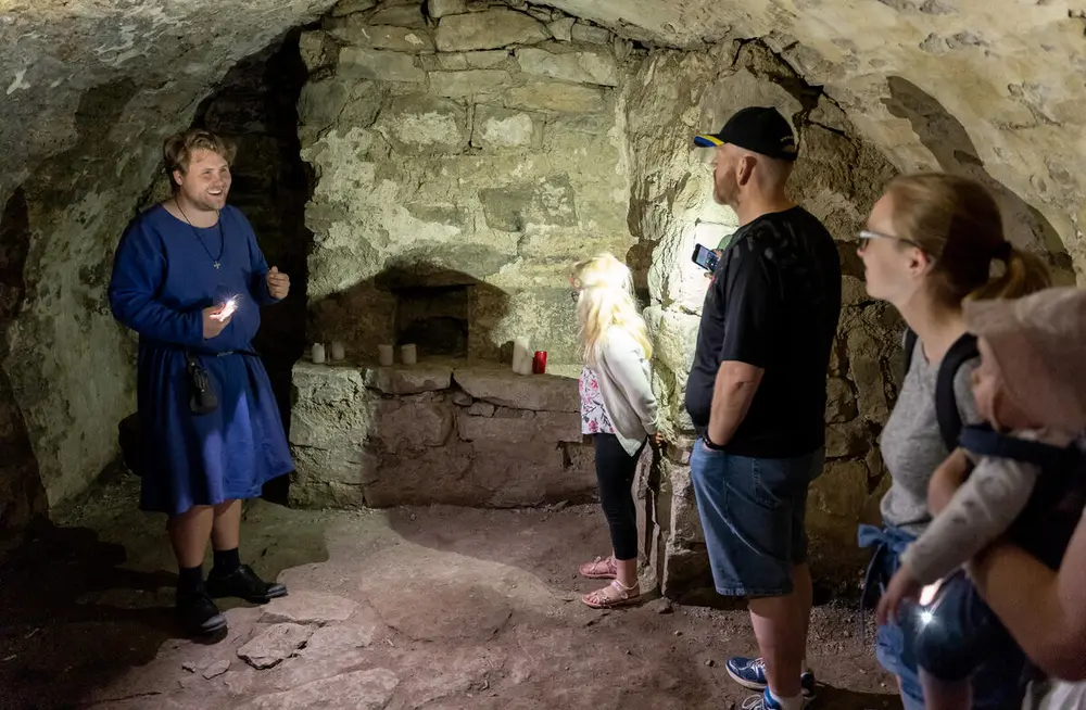 Middelalderkledd guide forteller spennende historier i mørke middelalderkjellere.