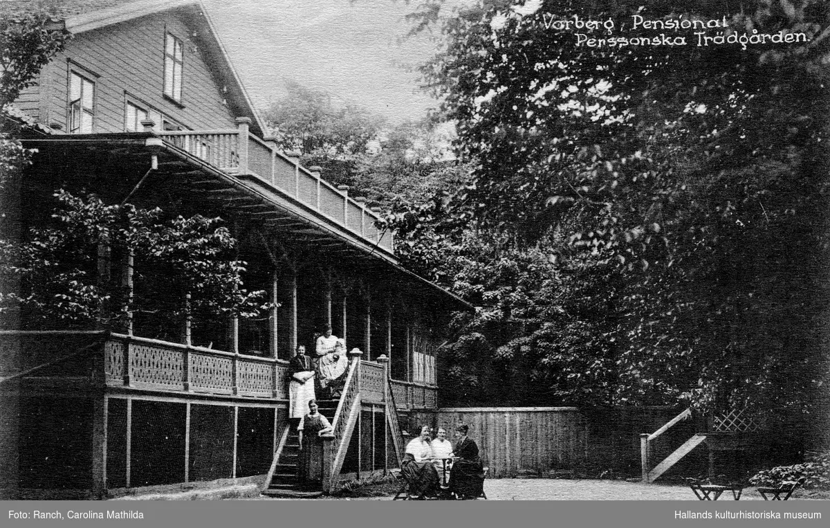 Vykort, "Varberg, Pensionat Perssonska Trädgården." Stavningen på denna inrättning har varierat och benämns ofta som Restaurang Pehrssonska trädgården. Här står tre kvinnor i trappan, en med en baby, och tre kvinnor sitter kring ett bord nedanför trappan. Troligen 1910-tal.
