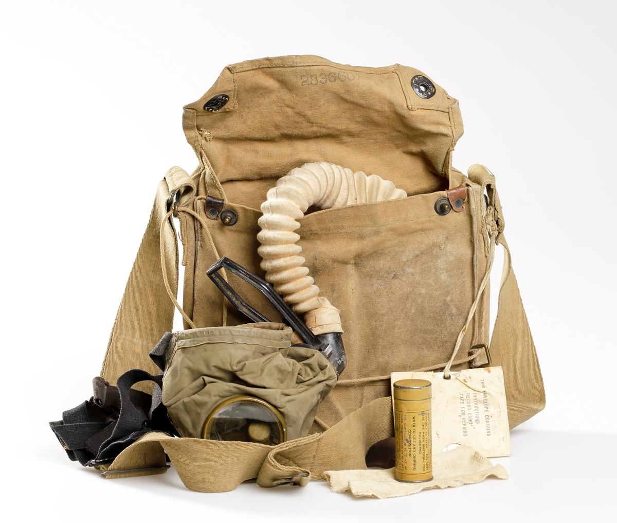 Gasmask bestående av väska, gasmask med slang och filter, samt behållare med imskyddsmedel med tillhörande putsduk. Väskan, att förvara och bära masken i, är i rektangulär form och tillverkad av kanvas, samt försedd med en bärrem i sadelgjord. I övre delen av väskan sitter ett lock som kan stängas med hjälp av tryckknappar. Lockets insida är stämplat med nummer "283660", och väskans utsida med soldatens namn "Carl E. Carlson", samt nummer "2083940" med bläck. På väskan är det även fastknutet med snöre, en instruktionsbok i fodral med texten "THE ENVELOPE CONTAINS INSTRUCTIONS RECORD TAPE FOR REPAIRS". Denna bok talar om hur masken används, samt innehåller också ett reparationskort. 
Gasmasken består av en glasögonförsedd mask som, med hjälp av remmar, krängs över huvudet för att skydda mot stridsgas. Från masken går en slang ner i väskan där en gul filterbehållare i plåt finns, som filtrerar luften innan den inandas. Botten av filtret är försett med ett membran som öppnas och stängs när man andas. Masken är stämplad med siffran "3" som är storleken, och numret "129T  381". Den gula filterbehållaren är märkt "CANCO" inom en oval. Den har även numret "148XH". En lädertunga vid maskens utblås är märkt "4819".
I väskan förvaras även en beige/gul plåtcylinder innehållande imskyddsmedel, samt en putsduk. Detta är till för att putsa gasmaskens glas, och detta görs med putsduken. Denna behållare har texten "THE CAN CONTAINS ANTI-DIMMING COMPOSITION FOR GAS MASKS......".